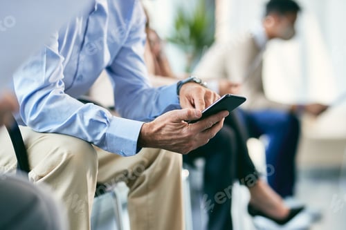 Preview: unrecognizable male candidate using smart phone while waiting for job interview.