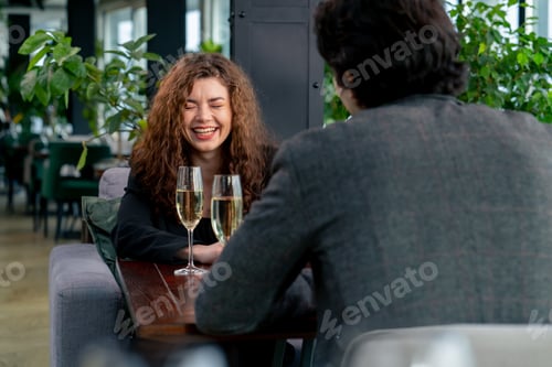 Preview: curly woman on a business meeting with a colleague or on a date with man with glasses of champagne