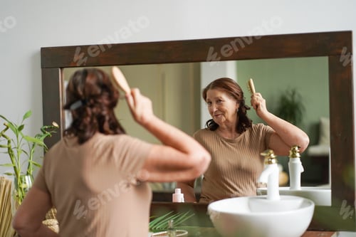 Preview: Slow motion view of old woman who carefully brushes her hair.