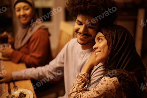 Preview: Happy Middle Eastern couple enjoying during meal at dining table.