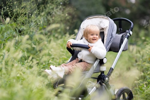 Preview: Cute healthy lovely baby with blonde hair wearing fashionable stylish clothing during walk at fall