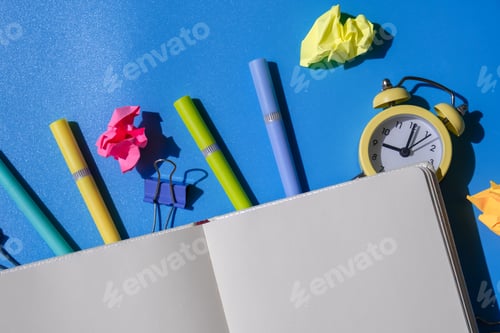 Preview: Frame border made of empty white paper notebook school stationery supplies and alarm clock. Copy