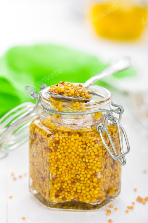 Preview: Mustard in glass jar on white wooden table closeup. Dijon mustard