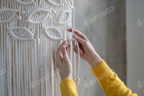 Preview: Freelancer woman working on half-finished macrame piece, weaves lamp shade for chandelier. Hobby.