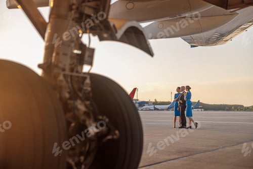 Preview: Full length shot of male pilot posing for photoshoot together with two air hostesses