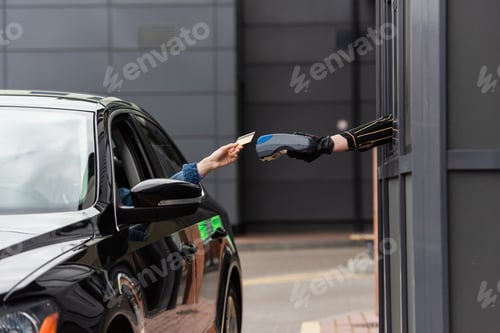 Preview: cropped view of woman in car holding credit card near payment terminal