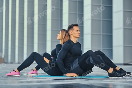 Preview: Fitness couple is exercising over modern building background.