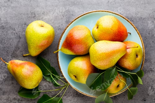 Preview: Fresh bio pear with leaves on the plate. Gray stone table.