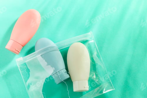 Preview: Cosmetic travel kit with plastic bag on turquoise background, top view. Space for text