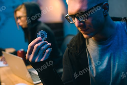 Preview: close-up shot of young handsome hackers holding bitcoin