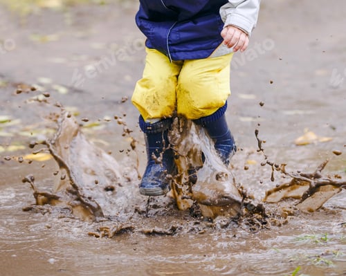 Preview: Happy kid jumping in the muddy puddles. Fall season activity
