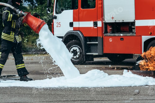 Preview: partial view of firefighter extinguishing fire with foam on street