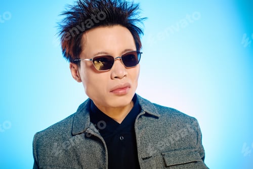 Preview: Stylish Asian man exudes confidence and charm in modern urban setting during bright daytime