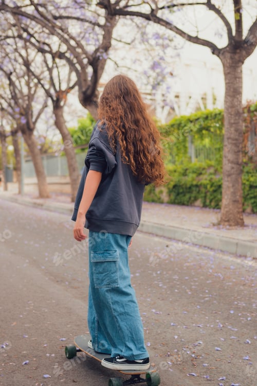 Preview: Young woman skates with her skateboard down a street