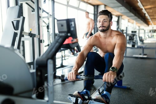 Preview: Young handsome man workout with rowing machine