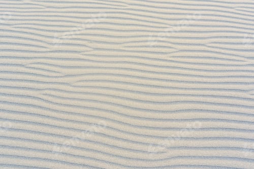 Preview: The beach with black sand. Background, texture, wavy pattern of the sand