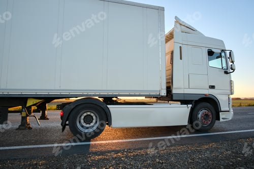 Preview: Semi-truck with cargo trailer driving on highway hauling goods in evening. Delivery transportation