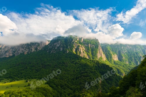 Preview: Rocky mountain range with trees and clouds
