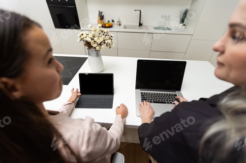 Preview: Mother is working with laptop when her daughter is using digital tablet.