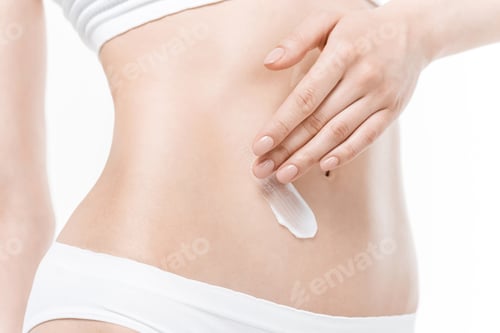 Preview: Close-up partial view of woman in underwear applying body cream on belly