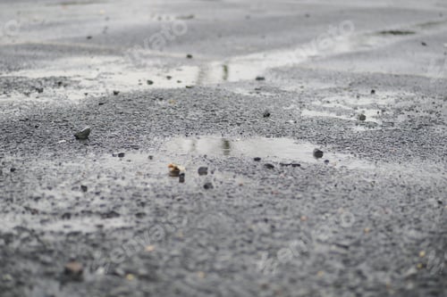 Preview: Wet asphalt shows puddles and small rocks after rain