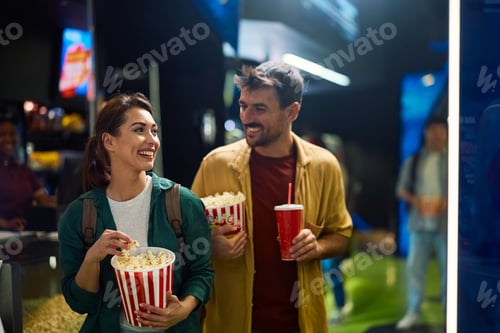 Preview: Young happy couple going to movie projection in cinema.