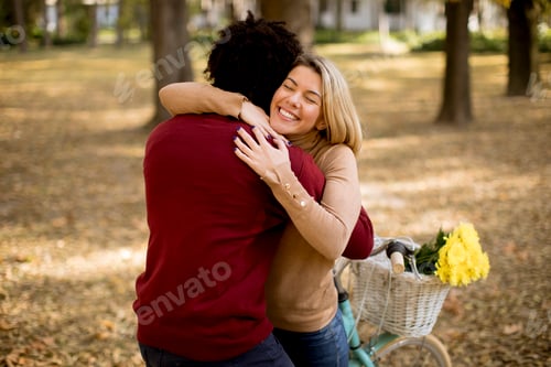 Preview: Multiracial couple with bicycle standing in the autumn park