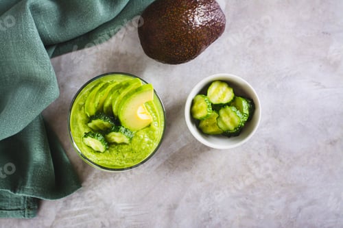 Preview: Green smoothie from avocado and cucumbers in a glass on the table top view