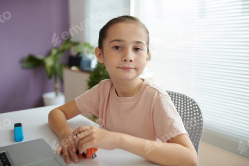 Preview: Portrait of Young Girl Sitting by Desk with Laptop and Toy Car