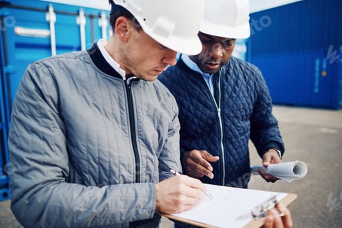 Preview: Two engineers standing in a container yard discussing shipping logistics
