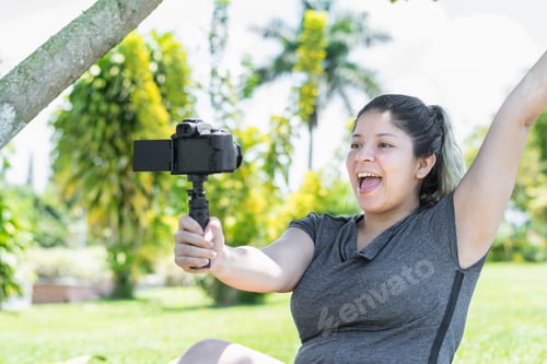 Preview: close-up of a young latina woman recording a video with a camera in her hand while being very happy.