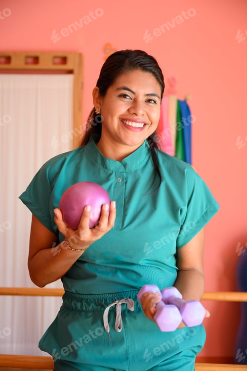 Preview: Physiotherapist smiling and holding weights and pilates ball in rehab center