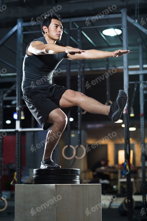 Preview: Young man doing box jump in crossfit gym