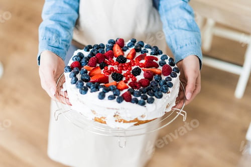 Preview: Young woman shwoing a cream cake with fresh fruits