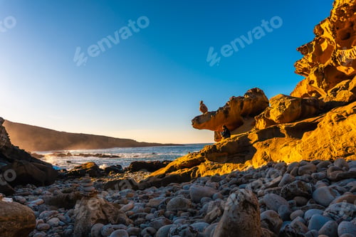 Preview: A young woman taking a photo at sunset in the stone cove on the Jaizkibel mountain