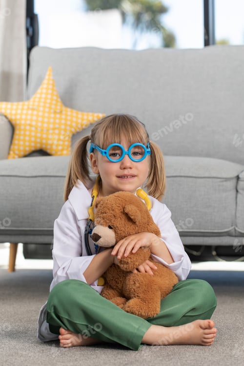 Preview: A little girl is playing in a doctor costume with a teddy bear. A child is playing at the hospital.
