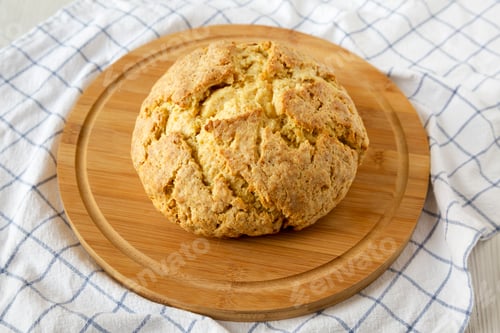 Preview: Homemade Irish Soda Bread on a round bamboo board, low angle view. Close-up.