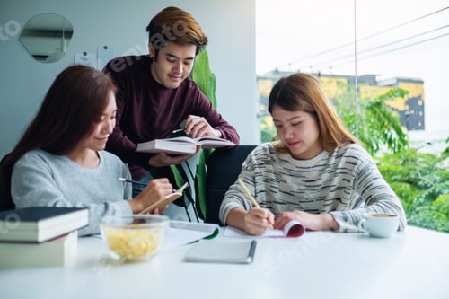 Preview: Group of young students tutoring and catching up workbook with friends