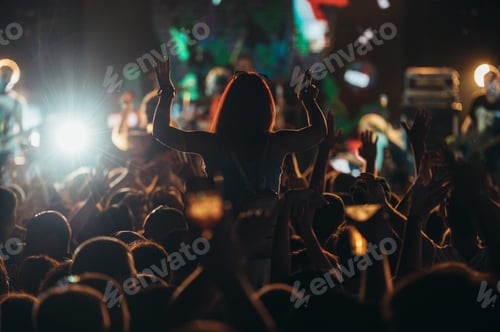 Preview: Silhouette of a woman with raised hands on a concert