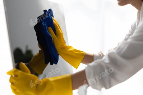 Preview: Asian cleaning woman use a cloth to wipe clean a computer using cleaning solution in her home office