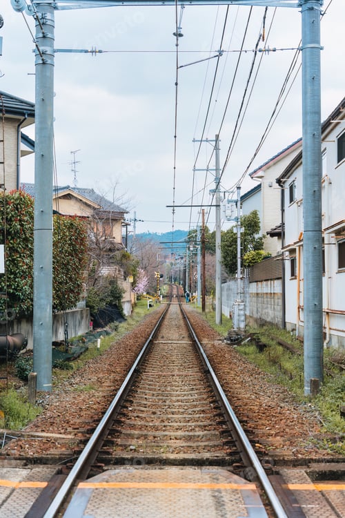 Preview: Railway track with wire cable among community during springtime in suburban