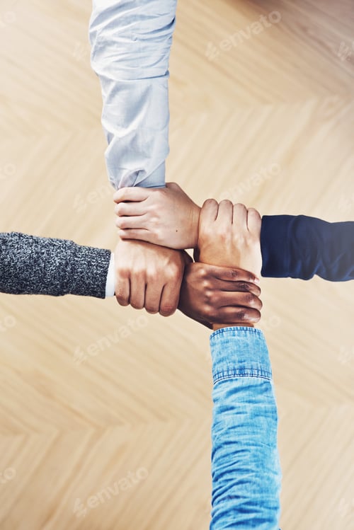 Preview: Cropped shot of a group of businesspeople linking their arms in solidarity