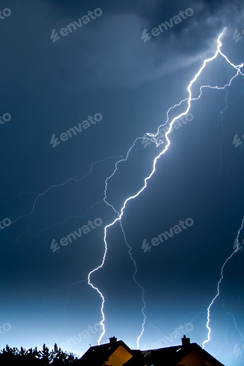 Preview: Vertical shot of lightning in the night sky over the village houses