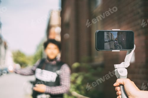 Preview: Behind the scene concept, professional news reporter making news outdoors with smartphone and gimbal