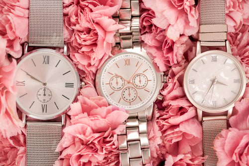 Preview: top view of wristwatches lying on blooming pink carnations