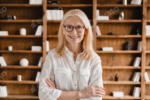 Preview: Businesswoman librarian psychologist teacher with arms crossed looking at camera in library office