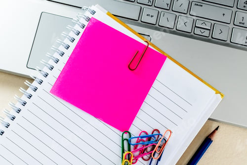 Preview: Top view of colorful paper clips on a blank notepad on a laptop