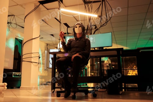 Preview: Hacker with mask looking at holographic image in augmented reality