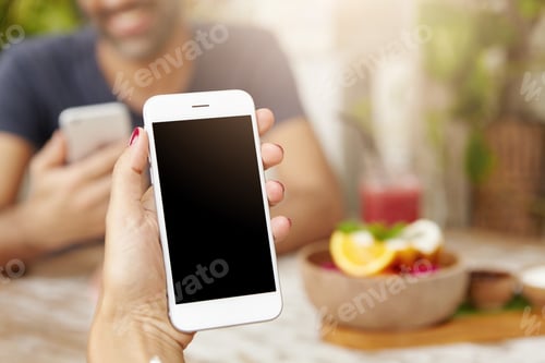 Preview: Cropped shot of Caucasian woman's hand holding generic mobile phone with blank copy space screen for