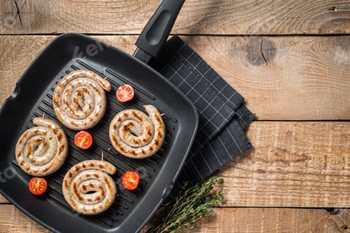 Preview: Fried on a grill pan spiral meat sausages with spices. Wooden background. Top view. Copy space